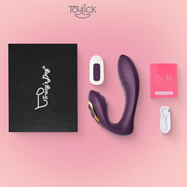 A flat-lay image showing the contents of the Toylick vibrator package. It includes a black "Tracy's Dog" branded box, the purple vibrator, a white remote control, a pink user manual, and the charging cable.